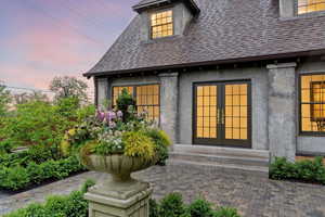 Property entrance featuring french doors, roof with shingles, and stucco siding