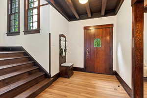 Entrance foyer featuring light wood-style floors, stairs, beamed ceiling, wood ceiling, and baseboards