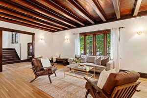 Living room featuring beamed ceiling, stairs, light wood finished floors, and wood ceiling