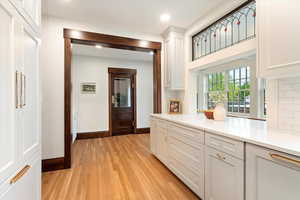 Kitchen with light wood-style floors, baseboards, tasteful backsplash, light countertops, and recessed lighting