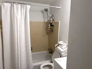 Full Bathroom with new toilet, tile patterned flooring, tub / shower combination, vanity, and a textured ceiling