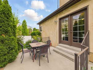 View of patio with entry steps, french doors, fence, and outdoor dining space
