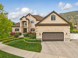 French country style house with stucco siding, concrete driveway, a gate, and a mountain view
