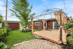 Rear view of property with a wooden deck, a yard, an outdoor structure, and a storage unit