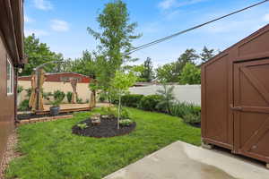 View of yard featuring an outdoor structure, a storage shed, a patio area, and a deck