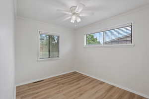 Unfurnished room featuring healthy amount of natural light, ornamental molding, light wood-type flooring, and baseboards