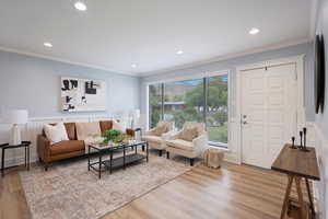 Living area featuring light wood-style flooring, crown molding, and recessed lighting