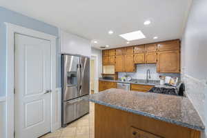 Kitchen with appliances with stainless steel finishes, a sink, a skylight, a peninsula, and backsplash
