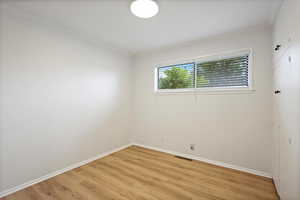 Unfurnished room featuring light wood-style floors, crown molding, and baseboards