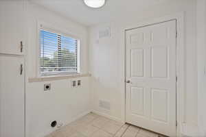 Clothes washing area with hookup for an electric dryer, baseboards, hookup for a washing machine, and light tile patterned flooring