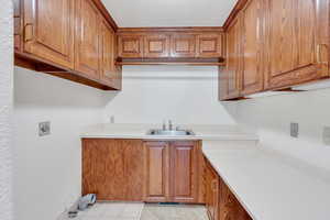 Laundry room has sink, storage, and large folding counter
