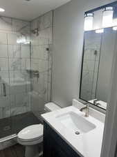 Bathroom with toilet, a shower stall, and vanity