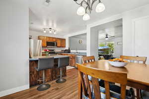 Dining area featuring wood finished floors, a ceiling fan, a chandelier, and baseboards