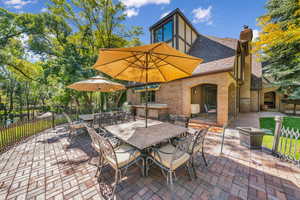 View of patio with fence, outdoor dining space, a fireplace, and grilling area