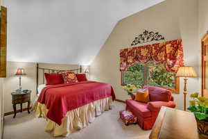 Carpeted bedroom with vaulted ceiling and baseboards