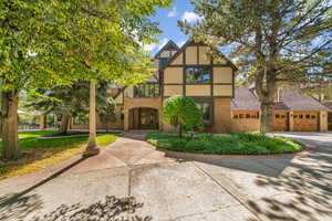 Tudor house featuring brick siding, an attached garage, driveway, and french doors