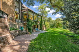 View of grassy yard featuring a patio and a sunroom
