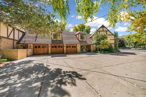 Tudor home with brick siding, driveway, a garage, and roof with shingles