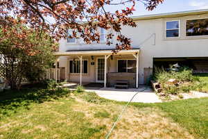 Rear view of house featuring a hot tub, a patio area, stucco siding, and a lawn