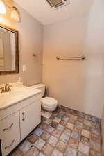 Bathroom with stone finish flooring, toilet, and vanity