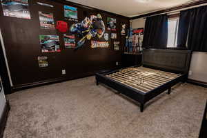Carpeted bedroom featuring crown molding and baseboards