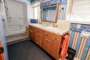 Bathroom featuring a shower stall, backsplash, and double vanity