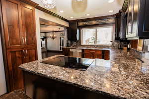 Kitchen with a sink, dishwasher, a chandelier, black electric stovetop, and decorative backsplash