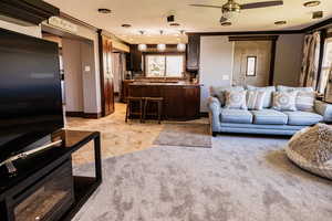 Living area with crown molding, a ceiling fan, and baseboards