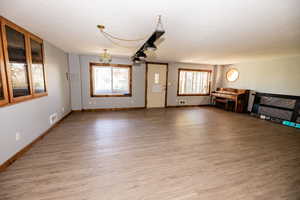 Unfurnished living room with baseboards, light wood-style floors, and a chandelier