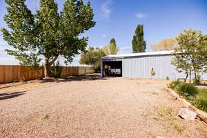 View of yard with fence, detached garage, and an outdoor structure.