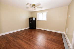 Unfurnished room featuring dark wood finished floors, a ceiling fan, and baseboards