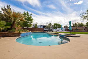 View of pool featuring fence, a patio area, and a pool with connected hot tub