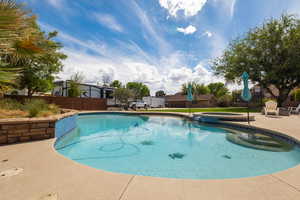 Outdoor pool with an in-ground hot tub, a patio, and fence