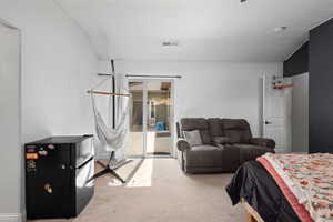 Bedroom with access to outside, carpet floors, and freestanding refrigerator