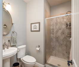 Full bathroom with a stall shower, toilet, baseboards, and a sink