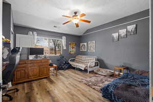 Office space with wood finished floors, a ceiling fan, lofted ceiling, and a textured ceiling