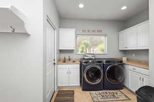 Washroom with cabinet space, washer and clothes dryer, recessed lighting, and light tile patterned floors