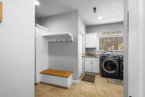 Clothes washing area with cabinet space, washing machine and dryer, a textured ceiling, recessed lighting, and light tile patterned flooring