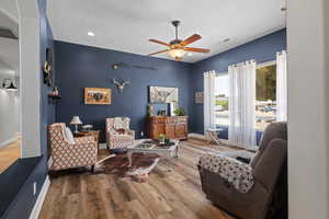 Living room featuring a textured ceiling, ceiling fan, wood finished floors, and baseboards