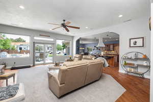 Living room featuring arched walkways, recessed lighting, a textured ceiling, a ceiling fan, and wood finished floors