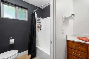 Full bathroom featuring toilet, shower / bathtub combination with curtain, and vanity