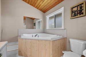 Full bathroom featuring wooden ceiling, toilet, vaulted ceiling, and a garden tub