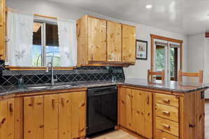 Kitchen with dishwasher, a sink, a peninsula, tasteful backsplash, and light wood finished floors