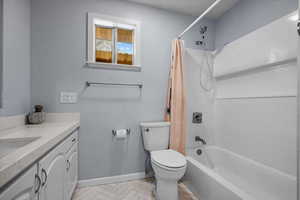 Full bathroom with baseboards, toilet, vanity, and shower / bathtub combination with curtain