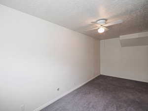 Unfurnished room featuring ceiling fan, a textured ceiling, carpet, and baseboards