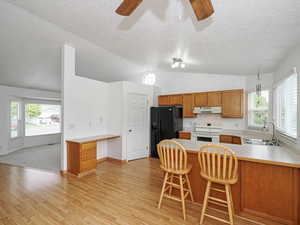 Kitchen with a sink, white electric range oven, under cabinet range hood, black refrigerator with ice dispenser, and ceiling fan
