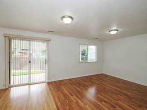 Empty room featuring wood finished floors, a textured ceiling, and baseboards