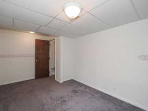 Spare room with carpet flooring, a drop ceiling, and baseboards
