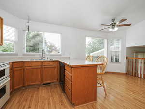 Kitchen featuring a sink, dishwasher, a peninsula, light wood finished floors, and a kitchen breakfast bar