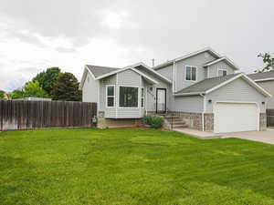 Tri-level home featuring roof with shingles, an attached garage, concrete driveway, and brick siding